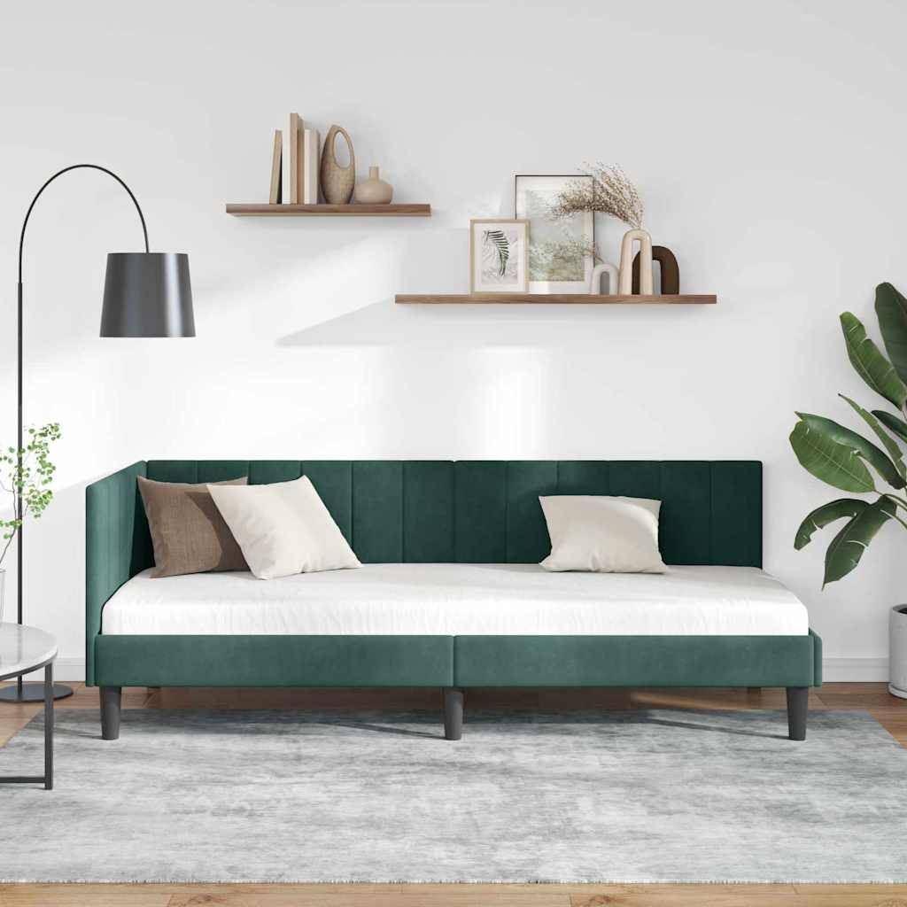 Modernes Wohnzimmer mit einem dunkelgrün gepolsterten Tagesbett, weißer Bettwäsche, Wandregalen, Stehleuchte und Topfpflanzen vor einer weißen Wand.