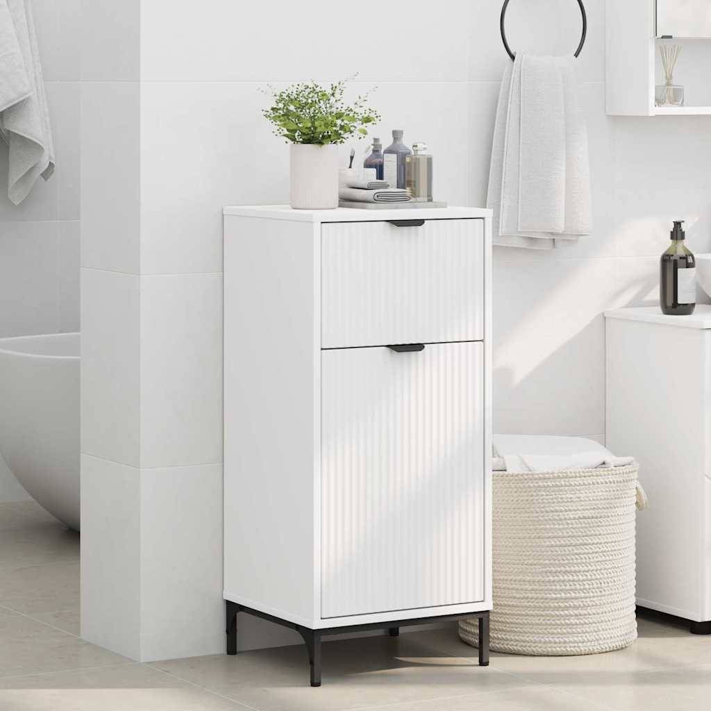 Eine Badezimmerszene mit einem weißen Schrank mit zwei Schubladen, der mit Körperpflegeprodukten und einer Pflanze bestückt ist. In der Nähe befinden sich ein Korb-Wäschekorb und ein Teil einer Badewanne.