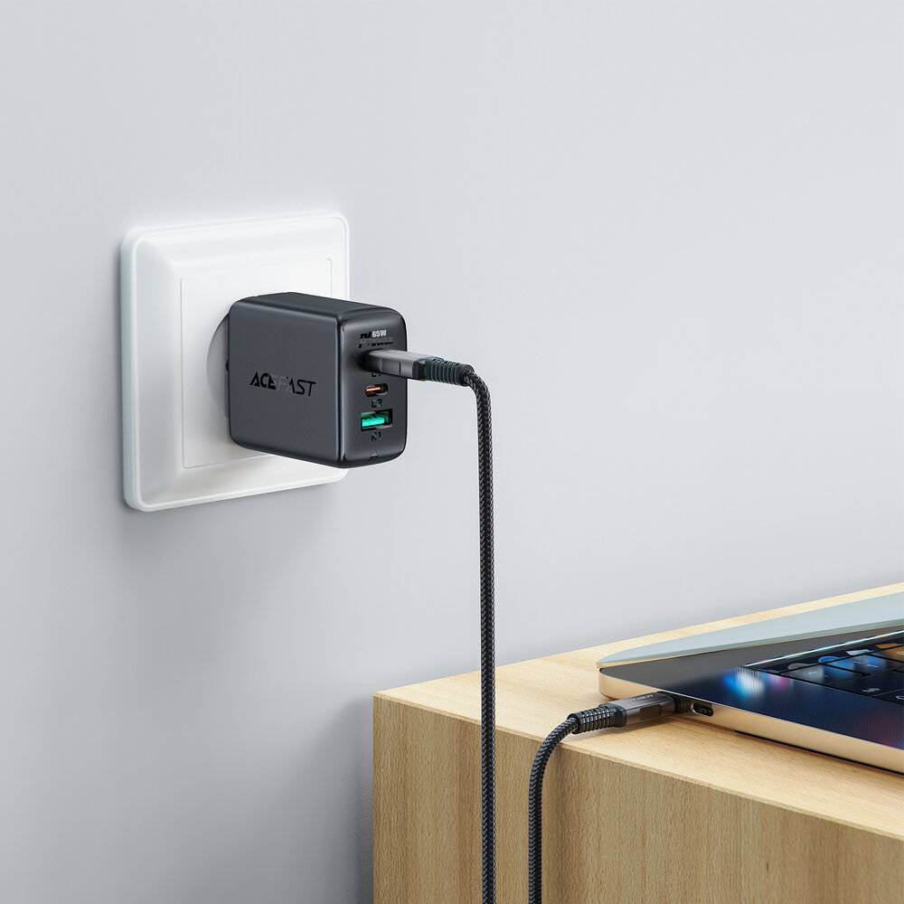 Eine Wandsteckdose mit einem USB-Ladegerät, das über ein Ladekabel mit einem Laptop verbunden ist.