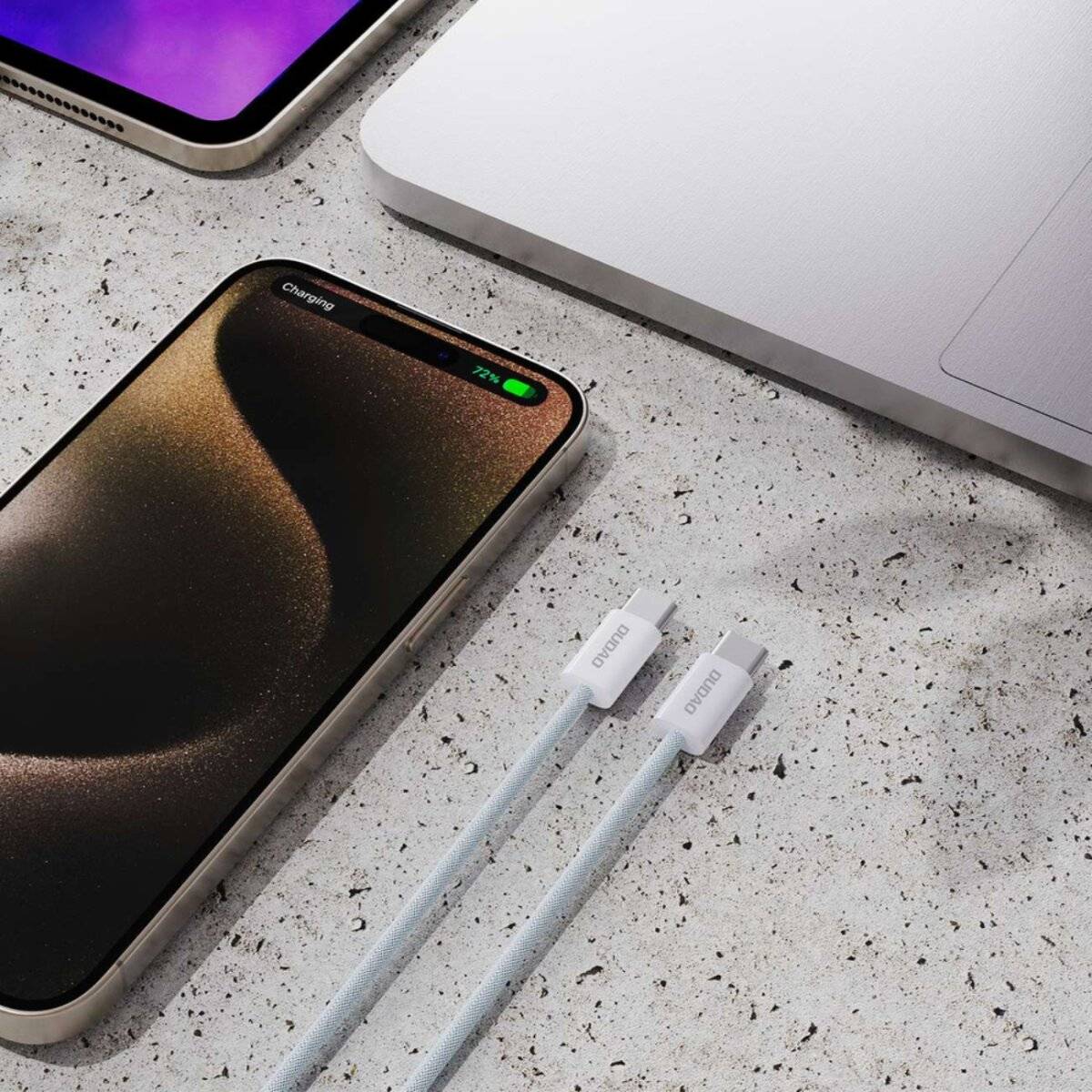 Smartphone und Laptop mit Ladekabeln auf einer gesprenkelten Oberfläche; das Telefon zeigt einen 