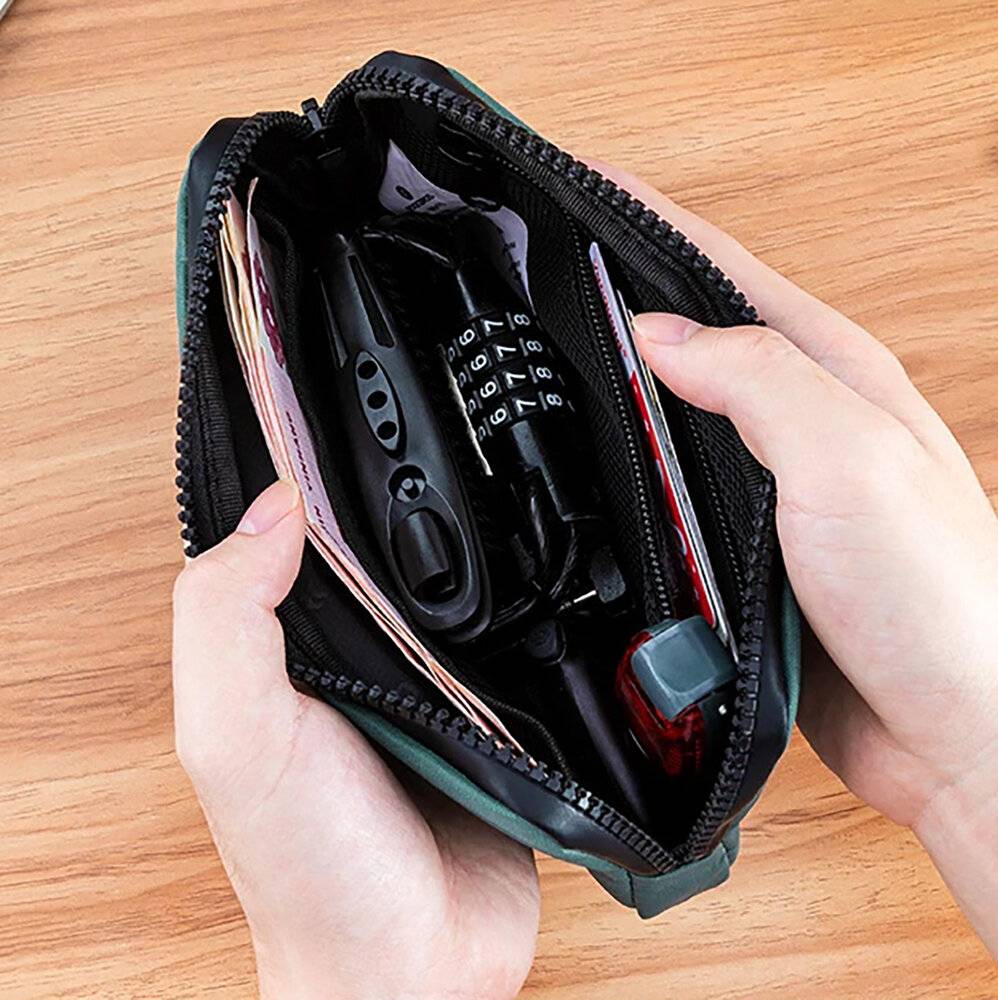 Eine Person hält einen offenen Federmäppchen, das Stifte, ein Schloss und andere kleine Gegenstände enthält, und ruht auf einer Holzoberfläche.