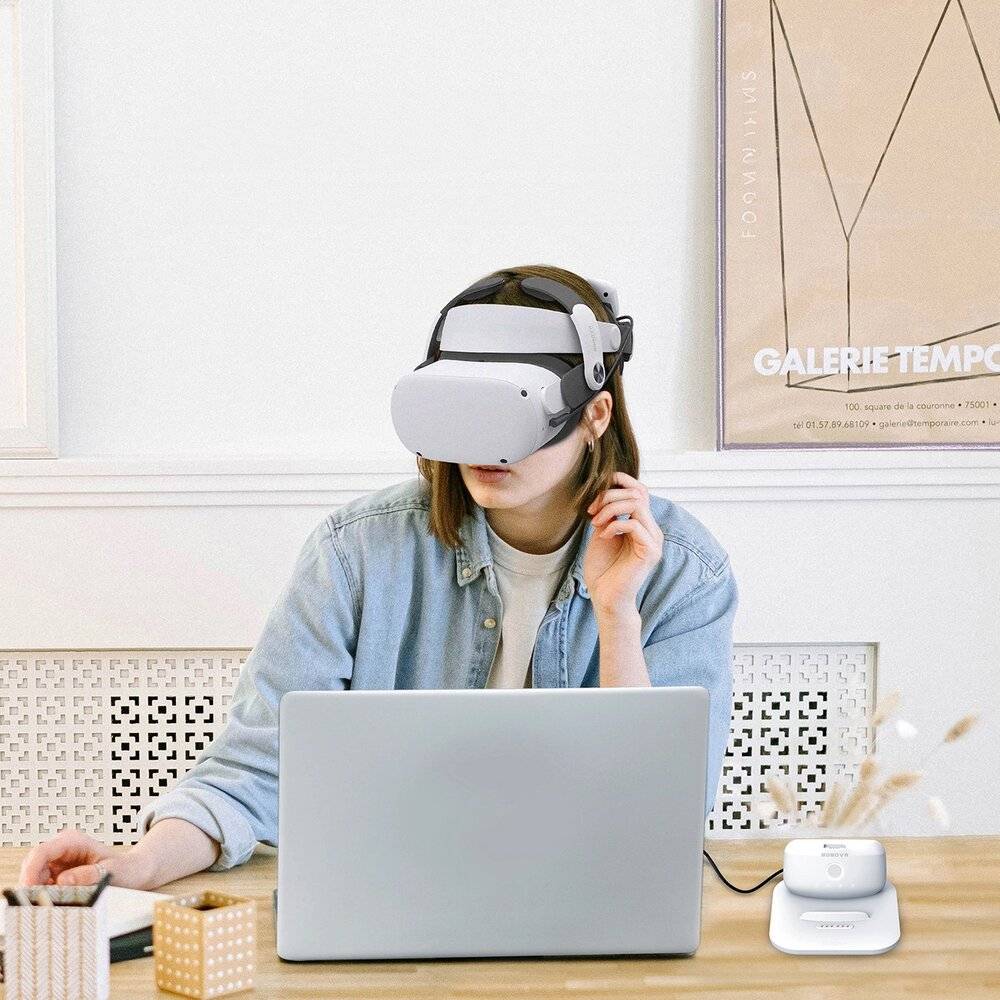 Eine Person trägt ein Virtual-Reality-Headset und sitzt an einem Schreibtisch mit einem Laptop und einem kabellosen Router, was auf eine Beteiligung an VR- oder Online-Aktivitäten hindeutet.