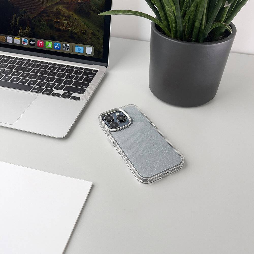 Ein Laptop mit angezeigtem Desktop-Bildschirm sitzt auf einem weißen Schreibtisch neben einem Smartphone mit glänzendem Gehäuse und einer Topfpflanze.