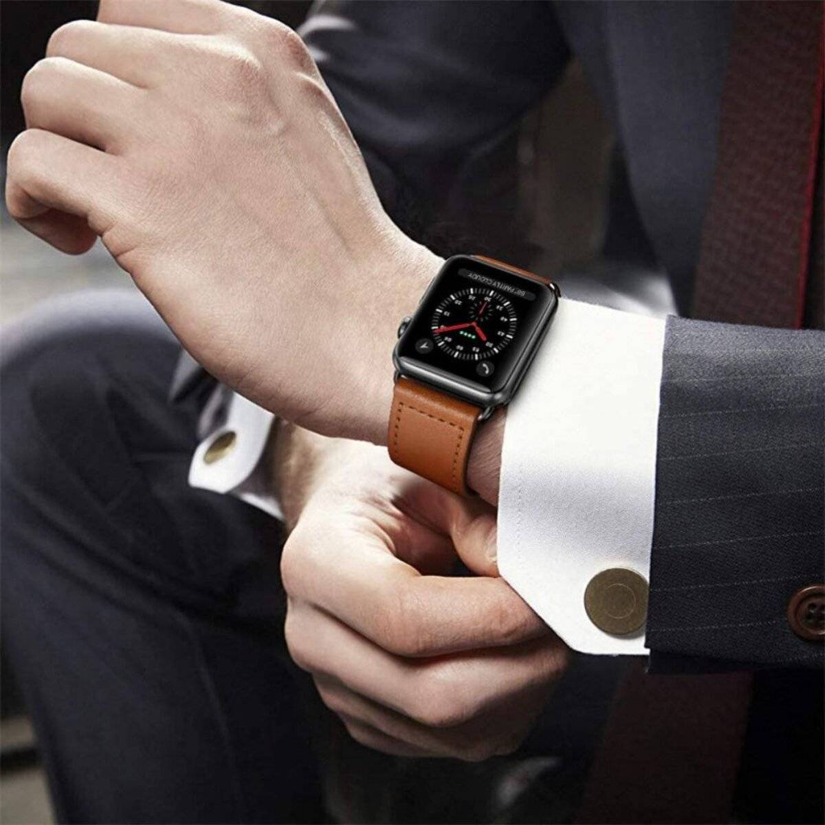 Eine Person stellt eine Uhr mit braunem Lederarmband an ihrem Handgelenk ein und trägt dabei einen Anzug, was auf eine formelle oder berufliche Umgebung hindeutet.