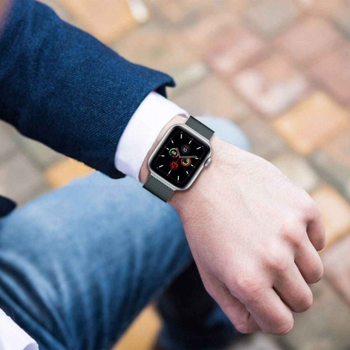 Eine Person trägt eine intelligente Uhr mit einem farbenfrohen Display an ihrem Handgelenk, das verschiedene App-Symbole anzeigt, vor einem unscharfen Außenhintergrund.