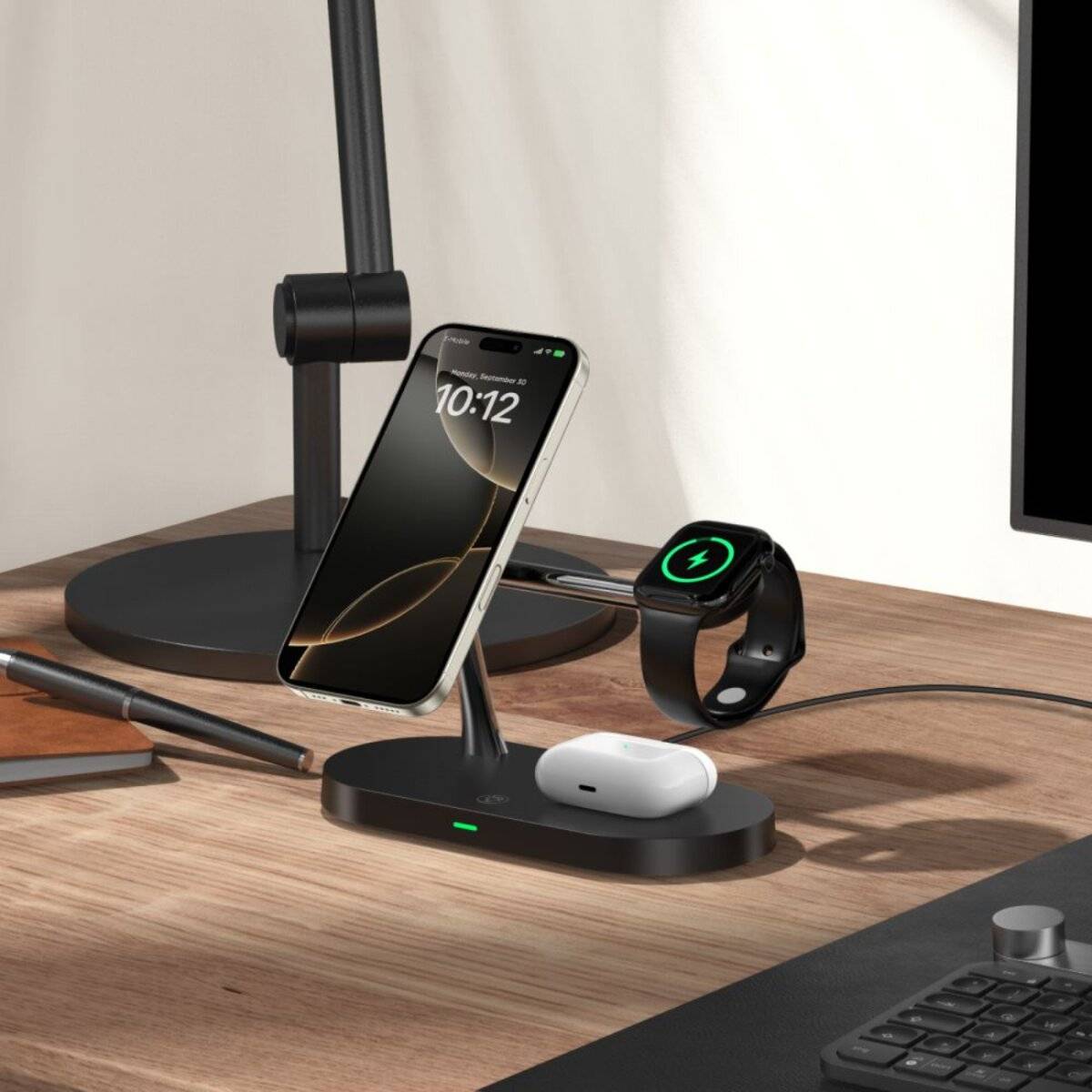 Ein Smartphone, eine Smartwatch und kabellose Kopfhörer liegen auf einem Holzschreibtisch. Das Telefon und die Uhr laden auf einem schlanken, schwarzen Ladegerät.