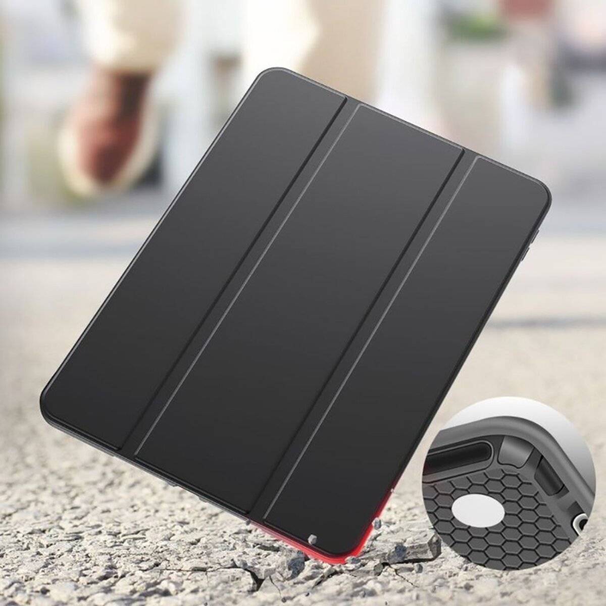 Ein geschlossenes schwarzes Tablet-Etui auf einem Gehweg mit einer kreisförmigen Vergrößerung, die eine Nahaufnahme der strukturierten Ecke des Etuis zeigt.