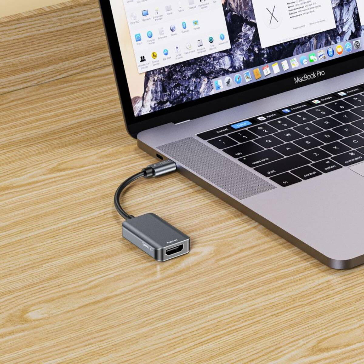 Ein Laptop auf einem Holzschreibtisch mit einem angeschlossenen USB-C-Hub mit mehreren Anschlüssen, der an der linken Seite des Geräts angebracht ist.