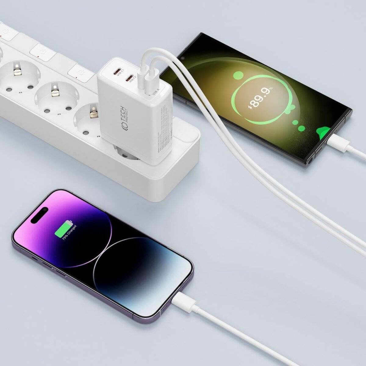 Ein Smartphone und ein Tablet werden aufgeladen und sind über ein Doppel-USB-Schnellladegerät mit einem Stromverteiler verbunden, das „89,9 %