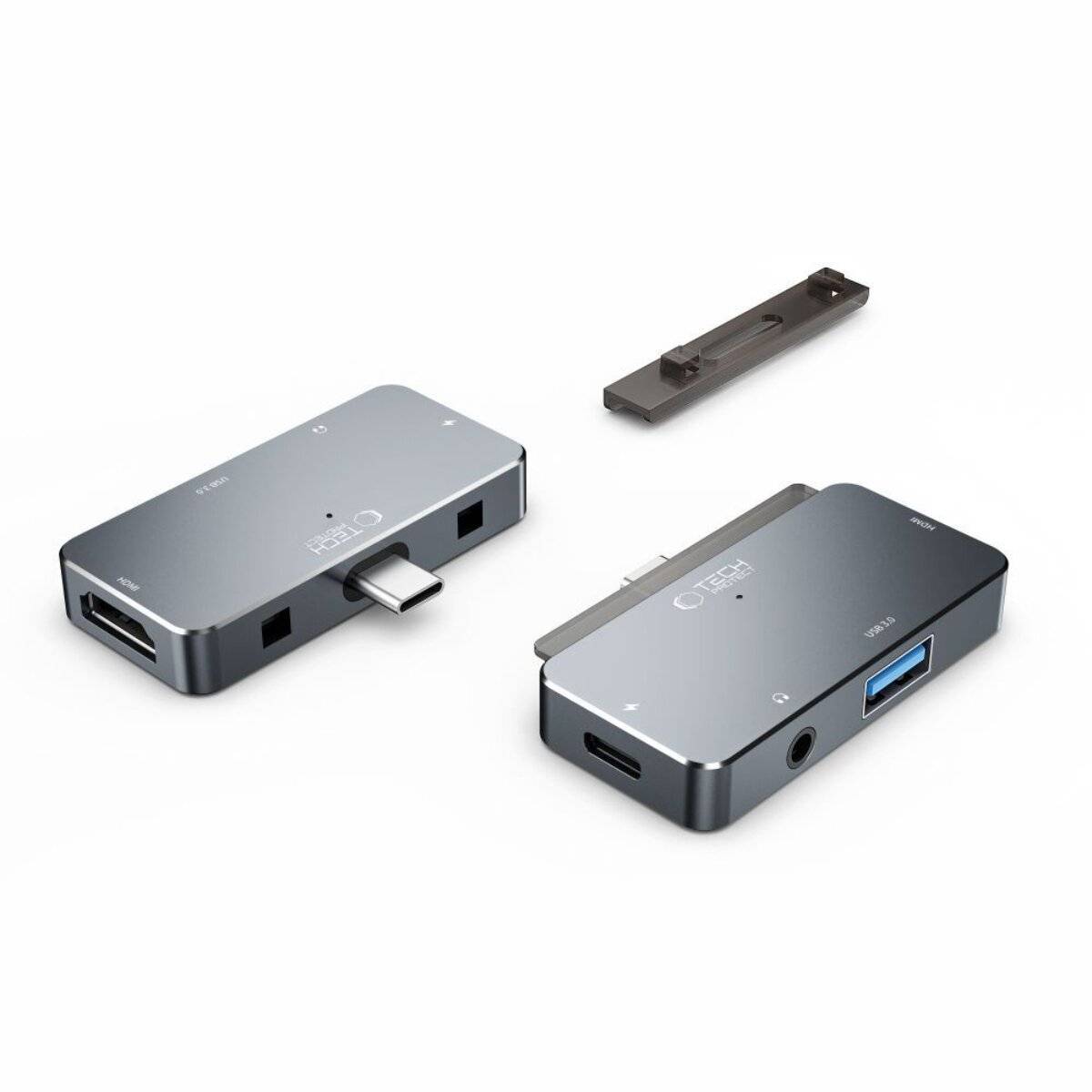 Zwei graue USB-C-Hubs mit mehreren Anschlüssen, darunter USB und HDMI, nebeneinander positioniert. Ein zusätzlicher kleiner Adapter liegt über ihnen.