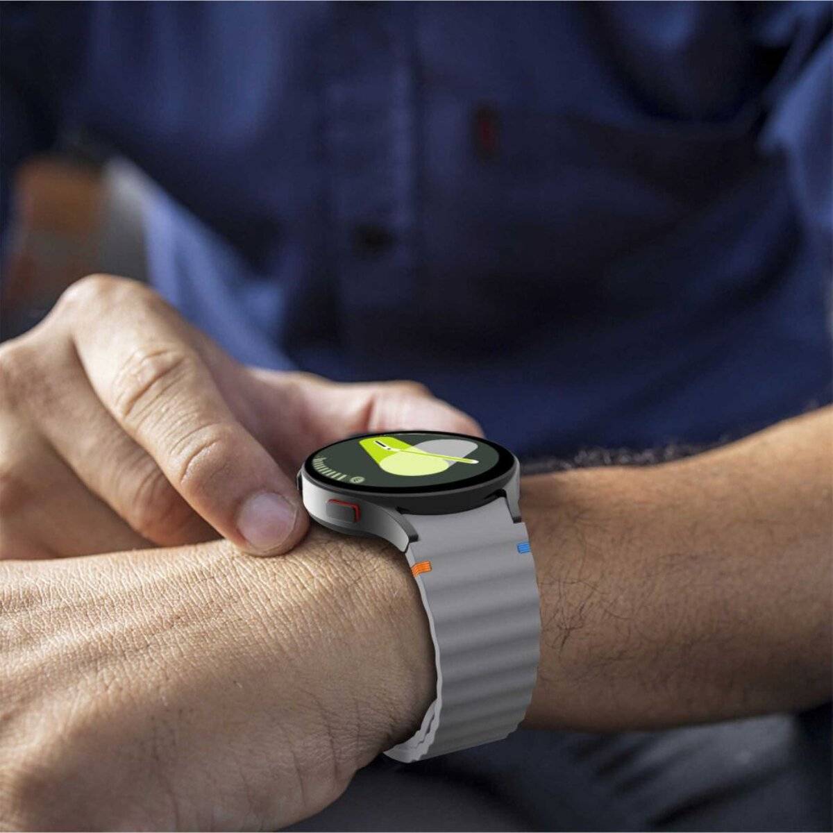 Eine Person trägt eine Smartwatch mit einer grünen und gelben Trainingsfortschrittsanzeige. Die Person ist mit einem blauen Hemd gekleidet.