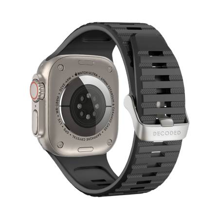 Eine Nahaufnahme einer Smartwatch mit metallischer Rückseite, schwarzem Armband und sichtbaren Sensoren, auf dem die Marke „DECODED