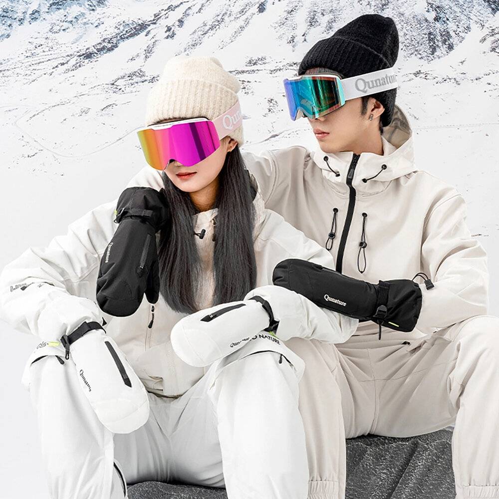 Zwei Personen in Winterausrüstung, einschließlich Skibrillen und Handschuhen, sitzen vor einer schneebedeckten Bergkulisse und deuten auf einen Ski- oder Snowboard-Ausflug hin.