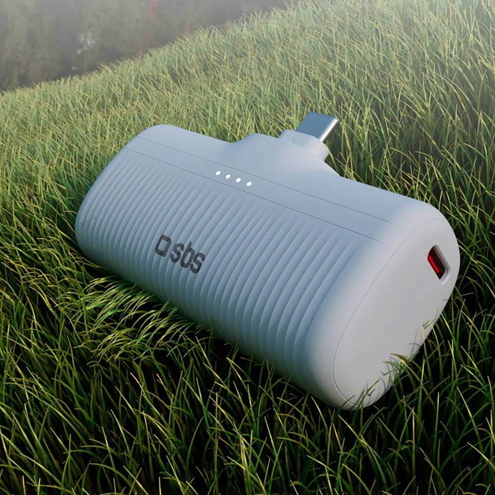 Eine weiße tragbare Powerbank mit gerippter Oberflächenstruktur und sichtbarem Logo auf Gras, mit einem Ladeanschluss und LED-Anzeigen.