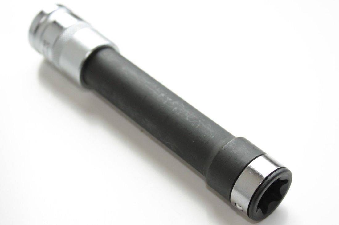 Nahaufnahme eines schwarzen Gummigriffs einer Taschenlampe mit einer silbernen Metallkante, die einen Teil einer Linse oder eines Reflektors an einem Ende zeigt.