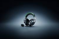 Ein schwarzes Gaming-Headset mit grünen Akzenten, mit großen gepolsterten Ohrpolstern und an­ge­bra­ch­tem Mikrofon, vor einem dunklen Verlaufshintergrund.