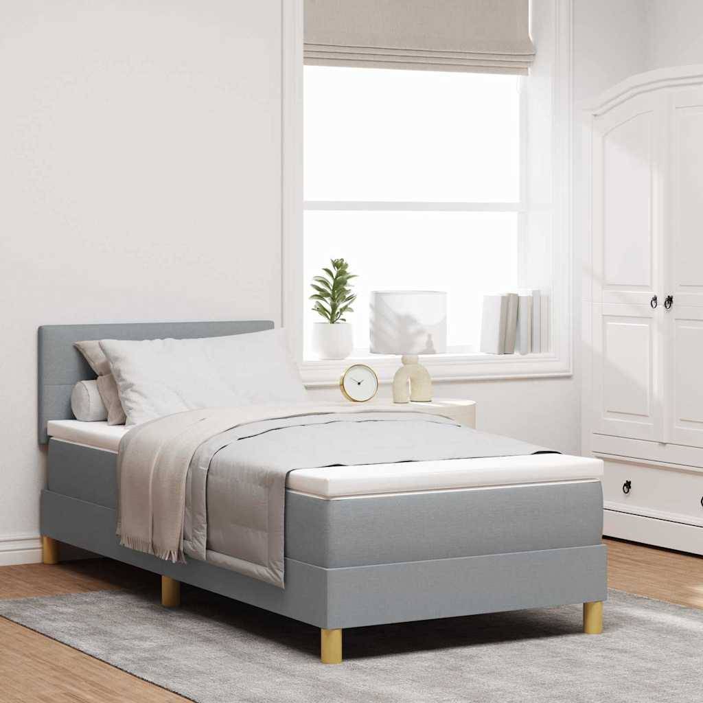 Ein minimalistisches Schlafzimmer verfügt über ein Bett mit grauer Bettwäsche, einen hellen Holzboden und ein Fenster mit natürlichem Licht. Eine kleine Pflanze schmückt das Nachttischchen.