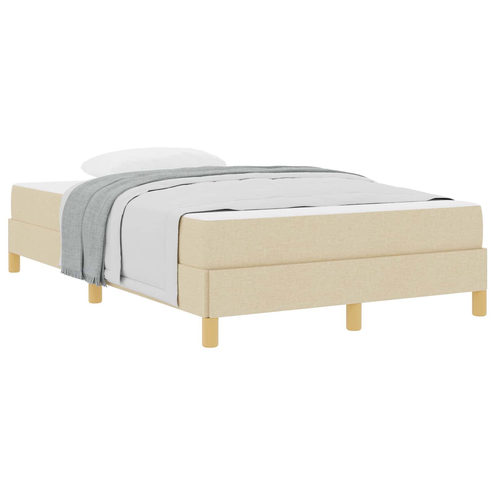 Ein minimalistisches beiges Bett mit hellen Holzbeinen, ausgestattet mit weißer Bettwäsche und einer grauen Wurfdecke, aus niedriger Perspektive betrachtet.