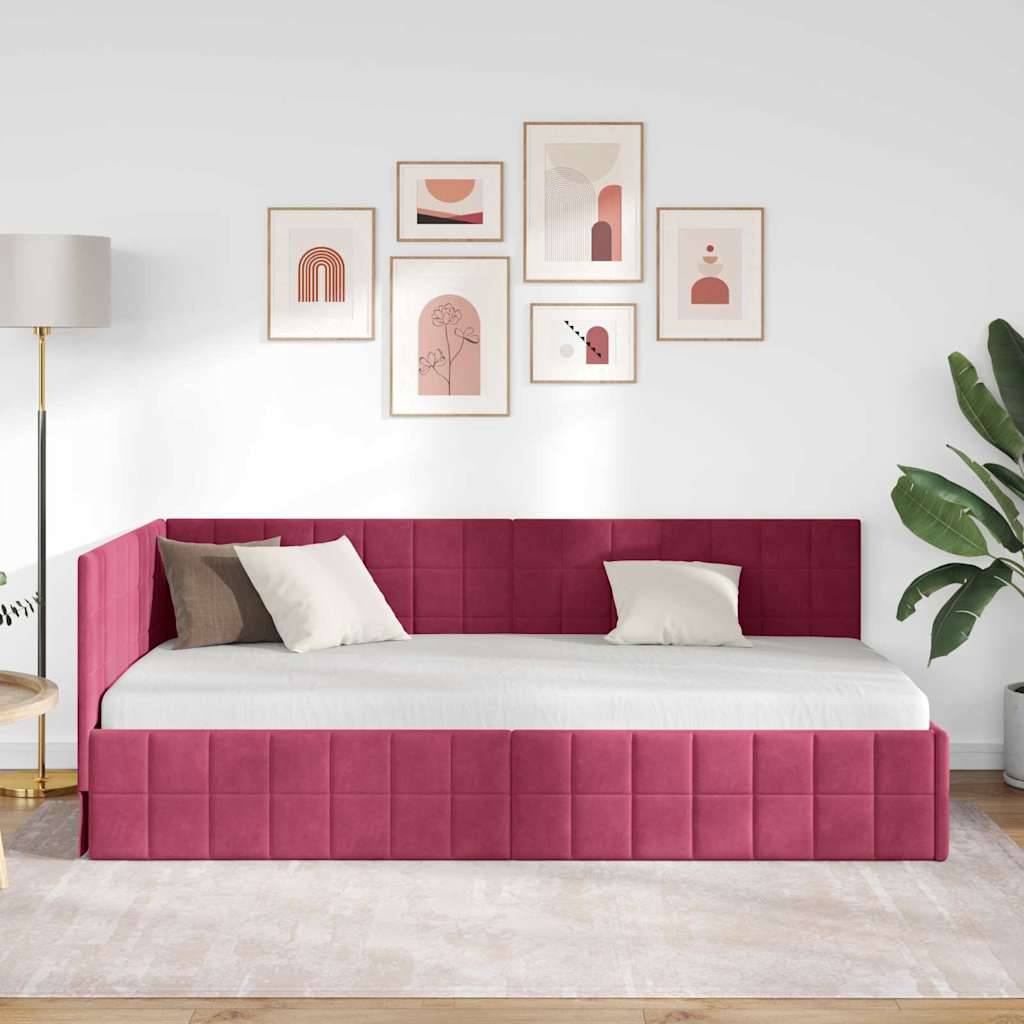 Ein modernes Schlafzimmer zeigt ein rot gepolstertes Bett mit weißer Bettwäsche, umgeben von gerahmter abstrakter Kunst und einer hohen Zimmerpflanze.