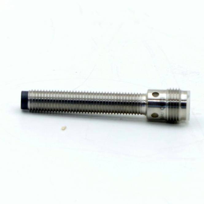 Ein metallischer zylindrischer Gewindescensor oder Befestiger, der horizontal auf weißem Hintergrund liegt.