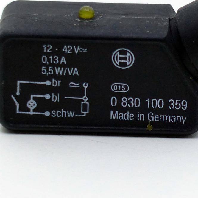 Nahaufnahme eines schwarzen elektronischen Moduls mit der Beschriftung '12-42V', '0,13A', '5,5 W/VA' und '0 830 100 359 Made in Germany', mit einem Schaltschema.