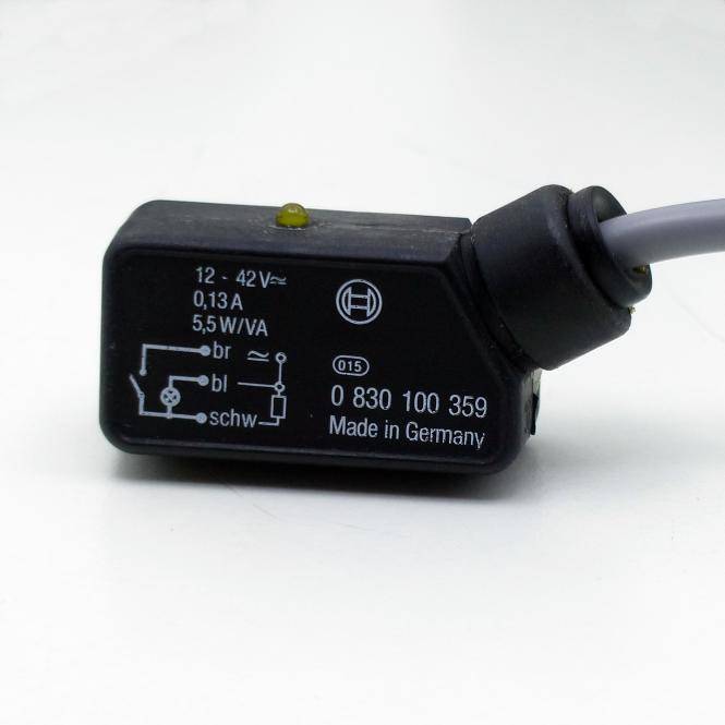 Schwarzes elektrisches Relaismodul mit grauem Kabel, gekennzeichnet mit 12-42V, 0,13A, 5,5W/VA, Teilenummer 0 830 100 359, Hergestellt in Deutschland.