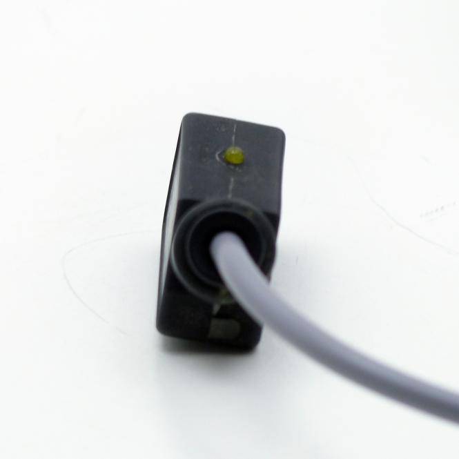 Nahaufnahme eines schwarzen elektronischen Steckers mit einem grau angeschlossenen Kabel, dargestellt auf weißem Hintergrund.