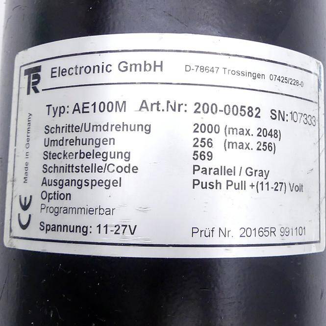 Nahaufnahme eines Gerätelabels von Electronic GmbH mit Modellnummer AE100M, Teilenummer 200-00582, 2000 Schritte, 256 Umdrehungen, Parallel-/Grauschnittstelle und 11–27V Stromversorgung.