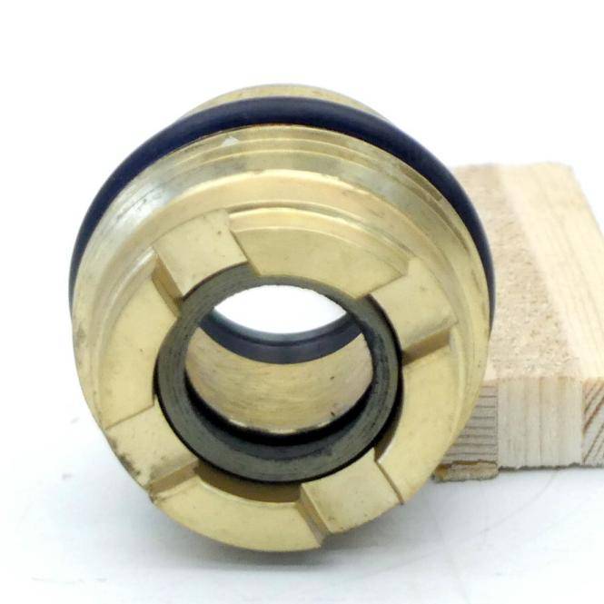 Nahaufnahme einer Messingmechanikkupplung oder eines Lagers mit einer zentralen kreisförmigen Öffnung, die auf einem kleinen Holzblock aufliegt.