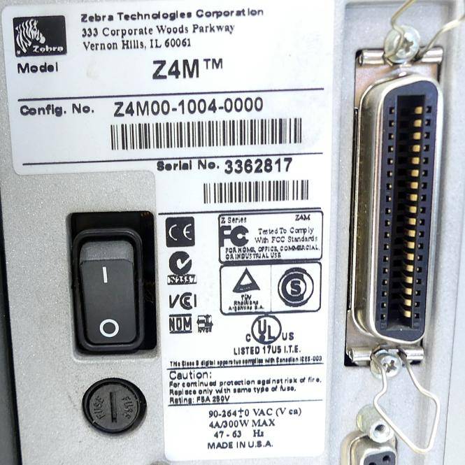 Nahaufnahme der hinteren Bedienplatte eines Zebra Z4M-Etikettendruckers mit Modell-, Konfigurations- und Seriennummernaufklebern, Netzschalter und Schnittstellen-/Anschlussverbindern.