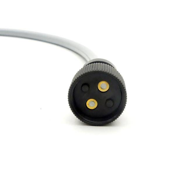 Nahaufnahme eines runden schwarzen Steckverbinders mit zwei vergoldeten Kontaktstiften auf einem hellgrauen Kabel vor weißem Hintergrund.