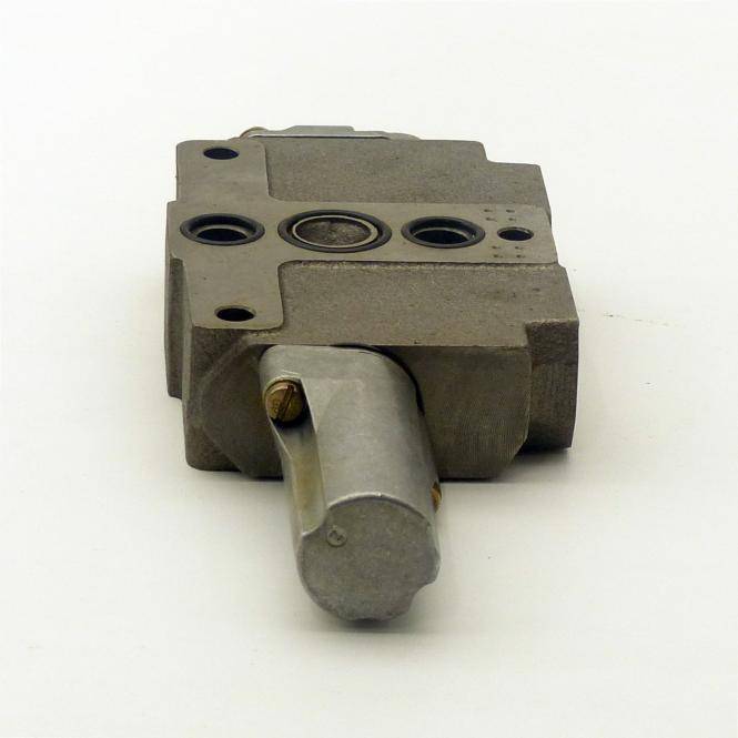 Metallischer mechanischer Ventil- oder Stellantriebblock mit mehreren kreisförmigen Anschlüssen und einem vorstehenden silbernen Hebel auf weißem Hintergrund.