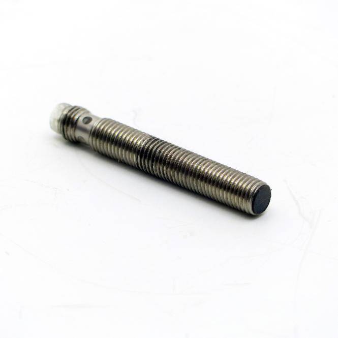 Nahaufnahme eines metallischen Gewindeschraubers oder einer Schraube, die diagonal auf weißem Hintergrund liegt.