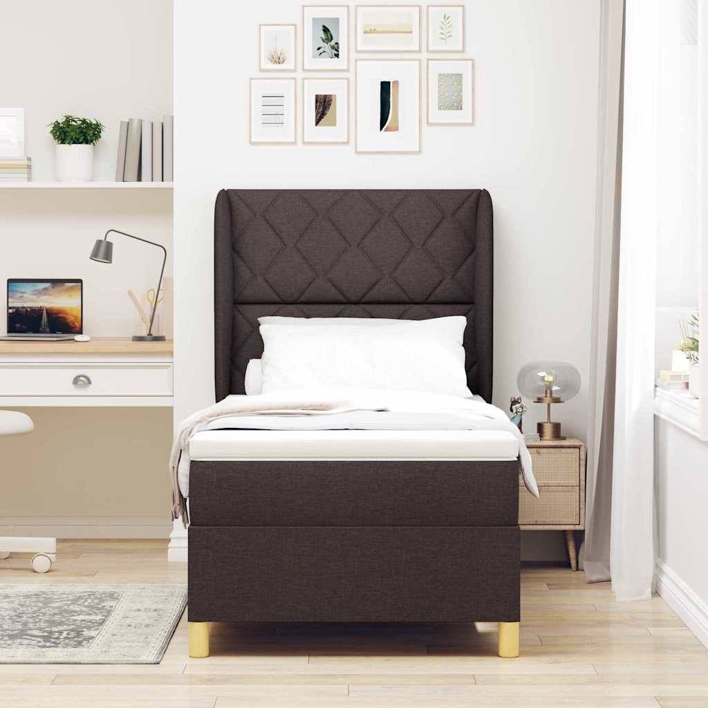 Ein modernes Schlafzimmer mit einem dunkel gepolsterten Bett, weißer Bettwäsche, einem Nachttisch mit einer Lampe sowie einem Schreibtisch mit einem Laptop und Büchern.