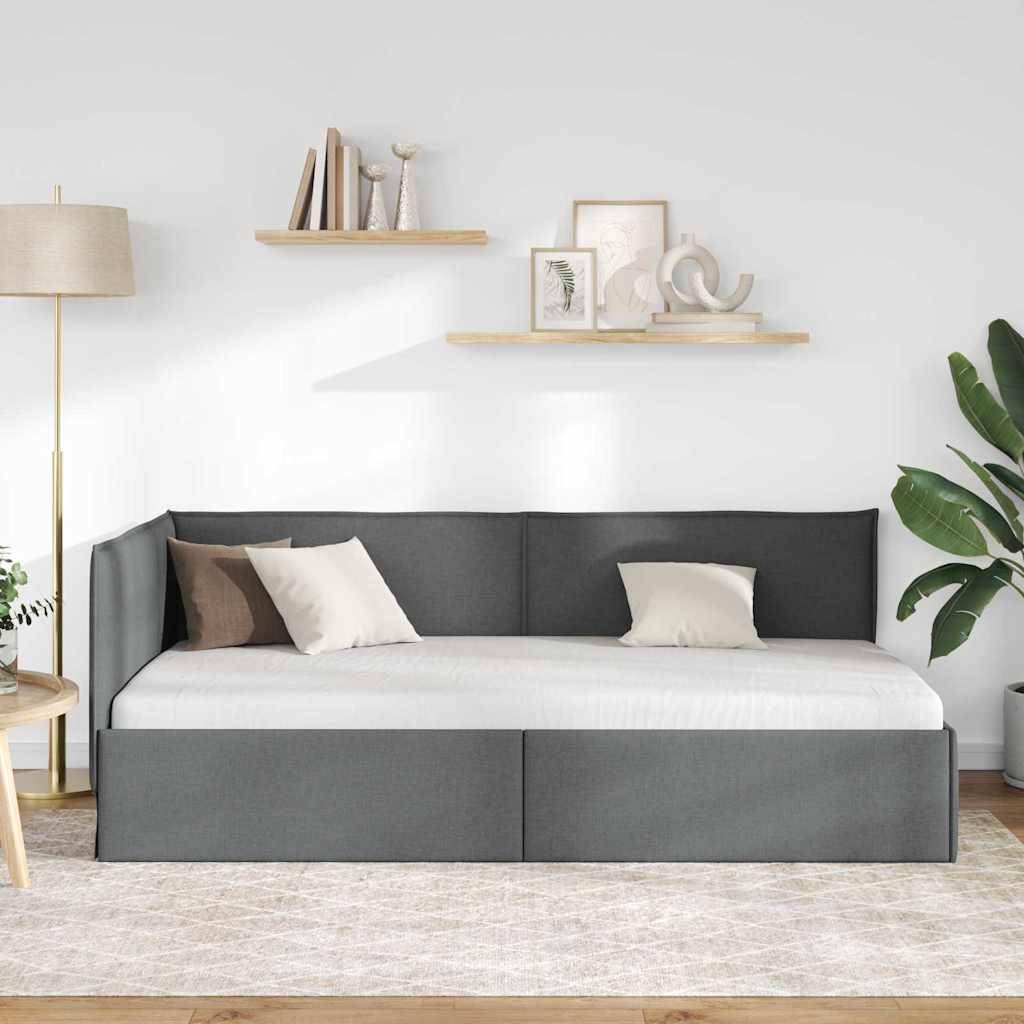 Ein modernes Wohnzimmer mit einem grauen Schlafsofa, weißen und beigen Kissen, zwei Holzregalen mit Dekoration, einer Stehlampe und einer Pflanze.