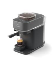 Eine Espressomaschine für die Arbeitsplatte mit grauer Oberfläche, die einen Espresso in eine kleine Glasstasse brüht. Die Maschine verfügt über einen Bohnenbehälter auf der Oberseite.