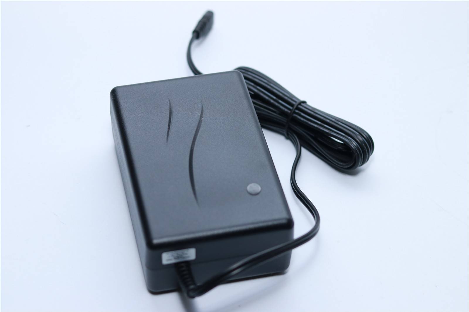 Ein schwarzer rechteckiger Stromadapter mit angeschlossenem Kabel auf weißem Hintergrund.