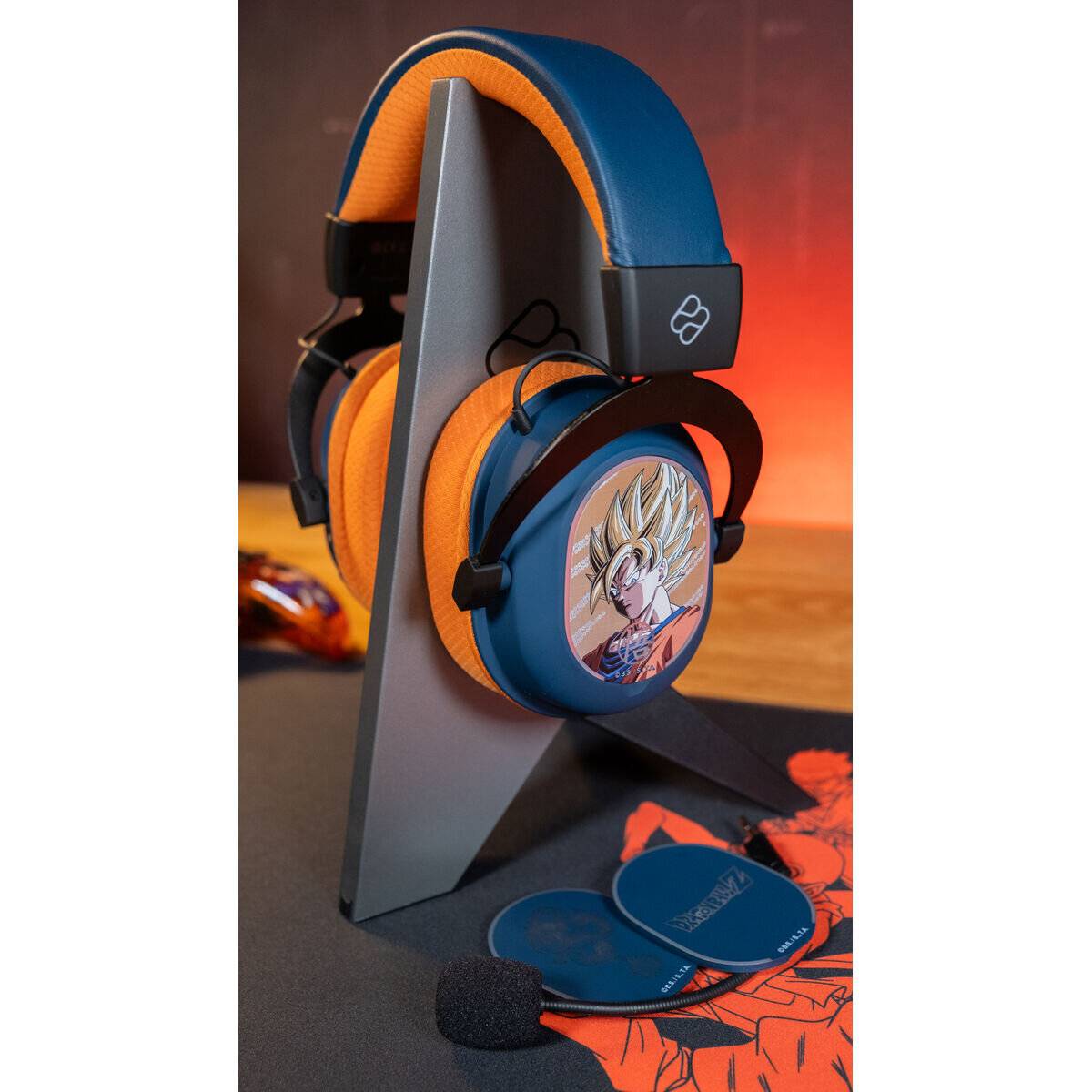 Blau-orange Over-Ear-Gaming-Kopfhörer auf einem Ständer, mit einem Anime-Charakter auf der Ohrmuschel und einem abnehmbaren Mikrofon in der Nähe.