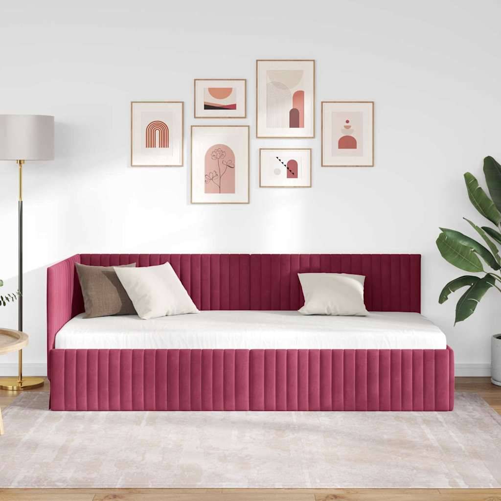 Modernes Schlafzimmer mit einem tief rosa gepolsterten Tagesbett, weißer Bettwäsche, neutralen Kissen, gerahmter abstrakter Wandkunst, Stehleuchte, Pflanze und hellem Teppich.