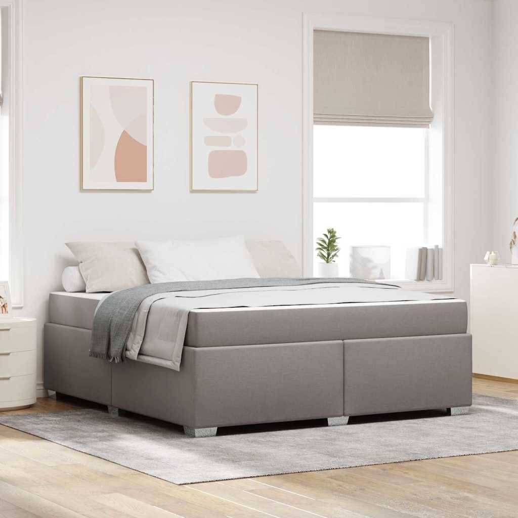 Grau gepolstertes Bett in einem hellen, minimalistischen Schlafzimmer mit weißer Bettwäsche, gerahmten Wandbildern und einem Fenster mit beigem Rollo.