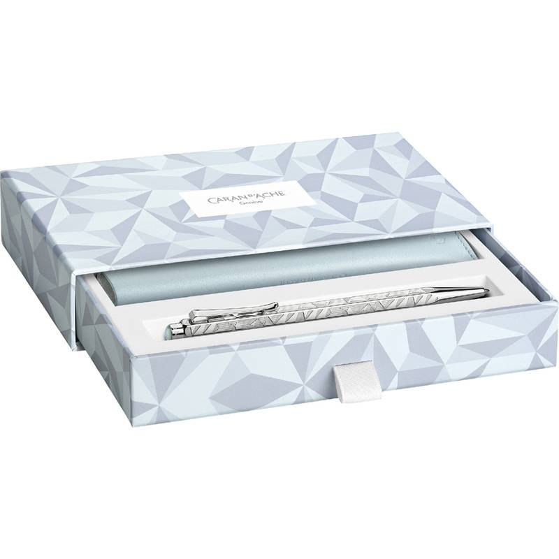 Geschenkbox mit geometrischem Muster, die einen luxuriösen Metallstift enthält, teilweise sichtbar mit geöffnetem Deckel, vor weißem Hintergrund.