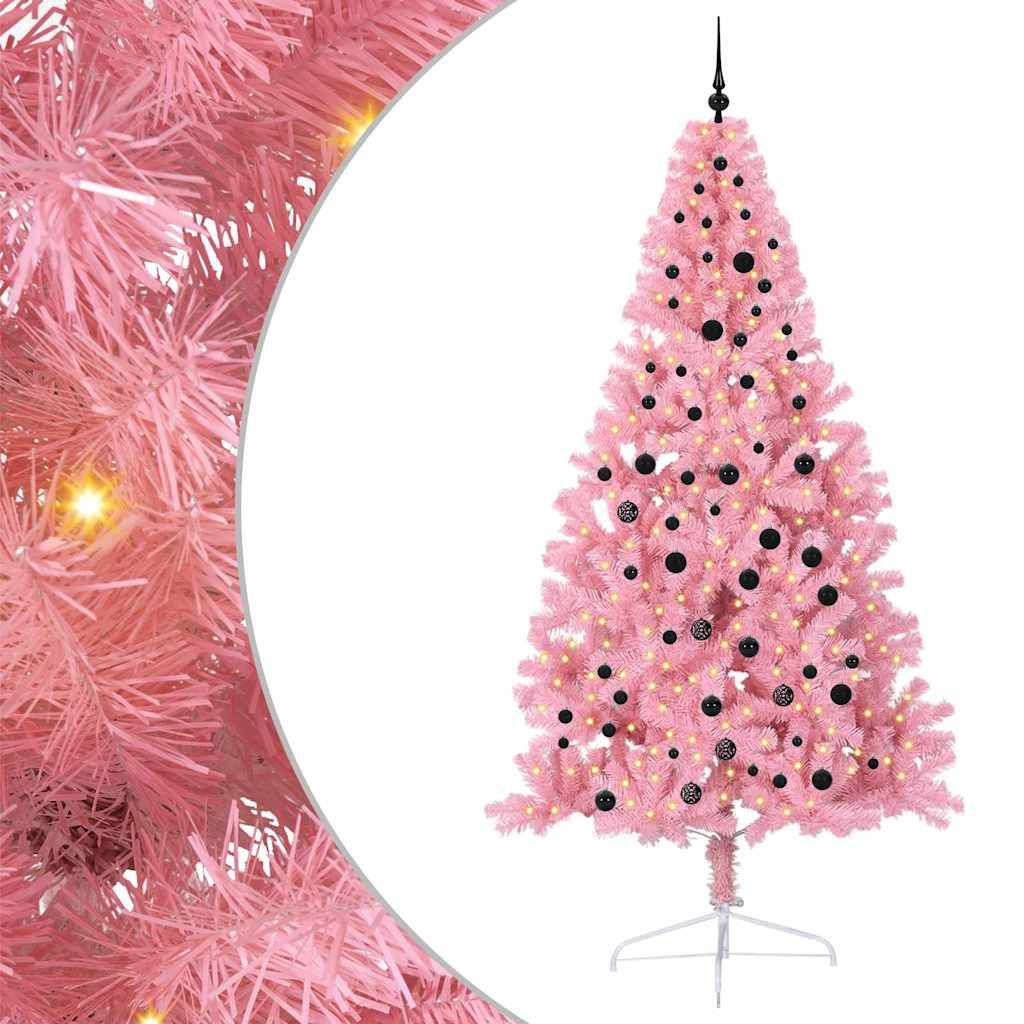 Ein rosa Weihnachtsbaum, geschmückt mit schwarzen Weihnachtskugeln und warmweißen Lichtern, steht auf einem Metallfuß vor einem sanft beleuchteten Hintergrund.