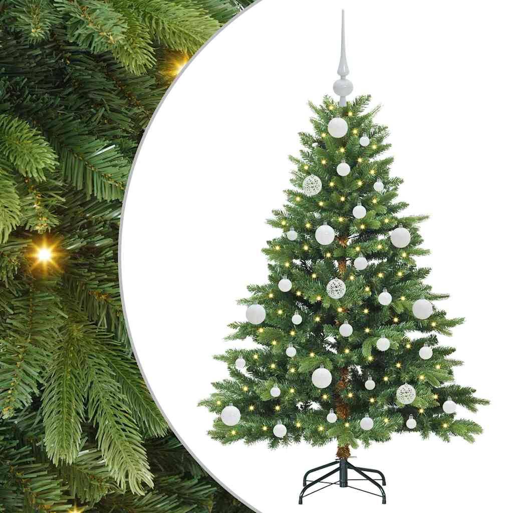 Dekorierter Weihnachtsbaum mit warmweißen Lichtern und weißen Kugeln auf einem Ständer, gezeigt vor weißem Hintergrund mit einer Nahaufnahme von grünen Ästen auf der linken Seite.