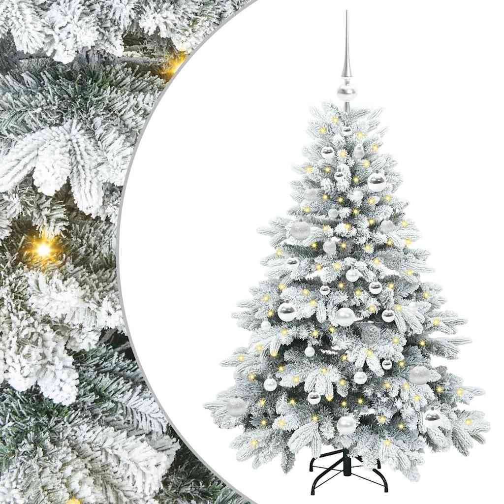 Mit Schnee bedeckter künstlicher Weihnachtsbaum mit warmweißen Lichtern, silbernen Kugeln und einer weißen Baumspitze auf einem Ständer; Nahaufnahme von bereiften Ästen auf der linken Seite.
