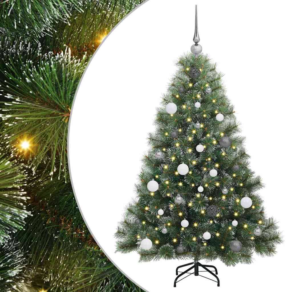 Ein geschmückter Weihnachtsbaum mit weißen Weihnachtskugeln und warmem Licht steht auf einem schwarzen Ständer und trägt einen silbernen Stern an der Spitze vor einem Tannenholz-Hintergrund.