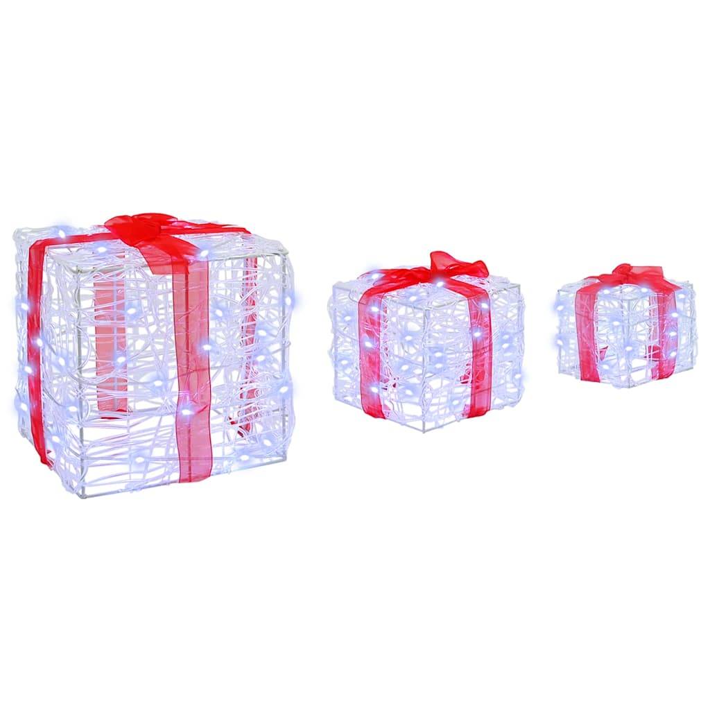 Drei beleuchtete weiße Geschenkboxen aus Draht mit roten Schleifen, in unterschiedlichen Größen nebeneinander angeordnet, deuten auf eine festliche Dekoration hin.