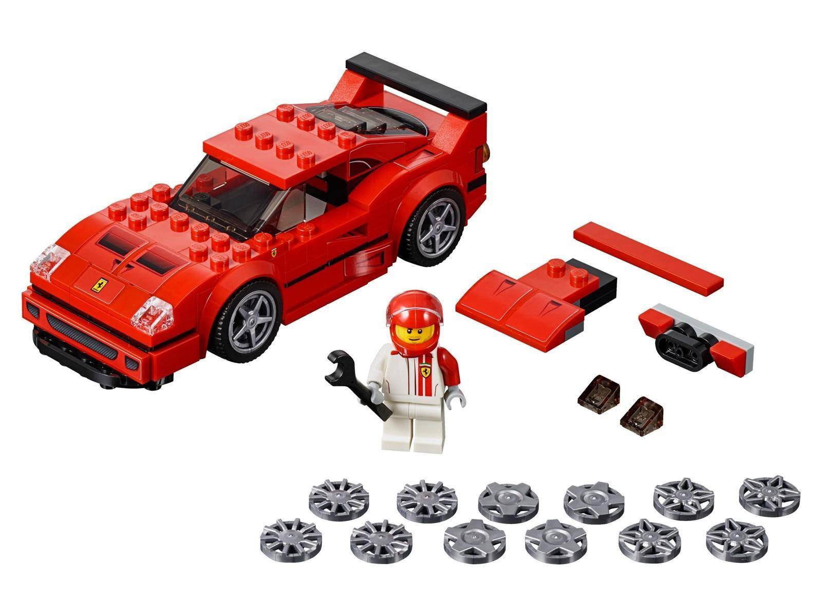 Roter LEGO-Rennwagen mit einer Minifiguren-Mechanikerin, losen Karosserieteilen und Ersatzradteilen auf weißem Hintergrund.