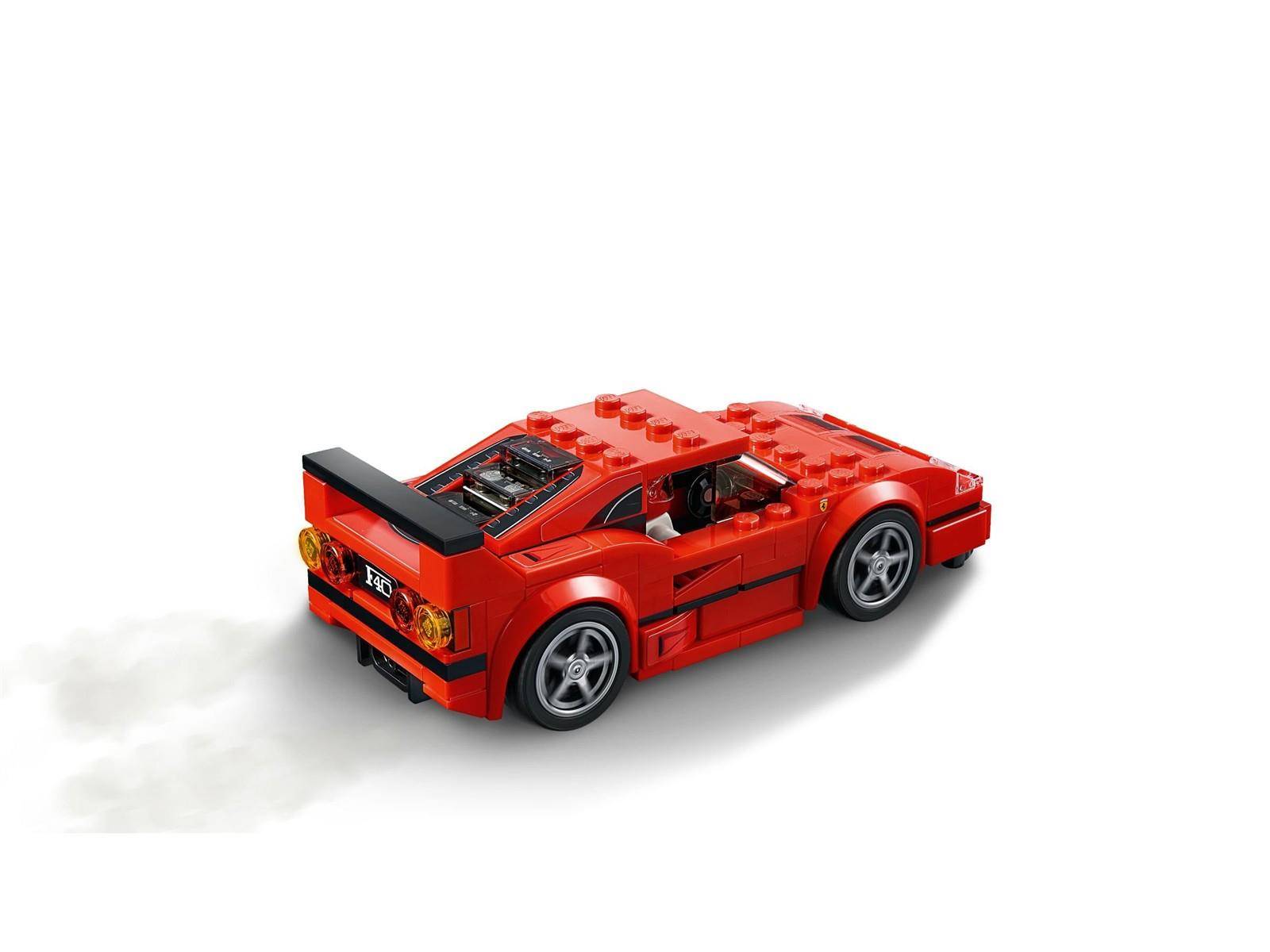 Rotes LEGO-ähnliches Sportauto in Dreiviertelsicht von hinten auf weißem Hintergrund, mit großem schwarzem Heckflügel und grauen Rädern.