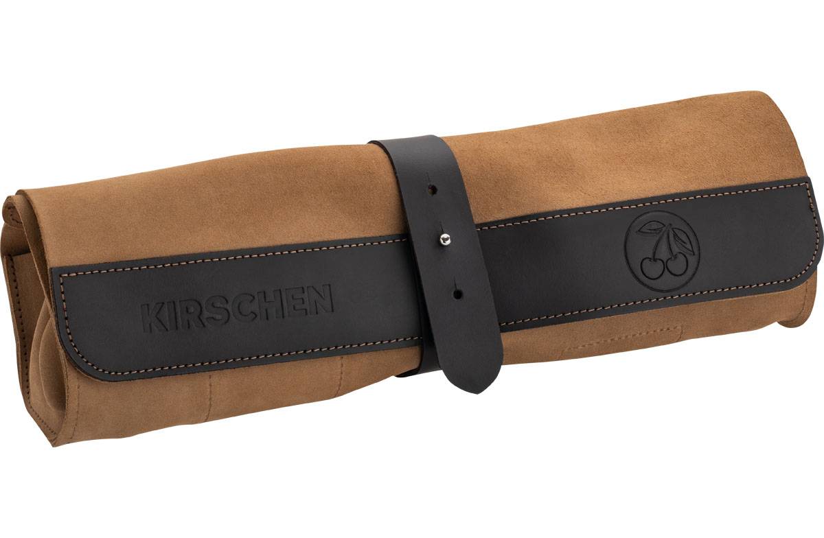 Eine beige Leinwand-Werkzeugtasche mit schwarzem Ledergurt und Schnalle, auf der rechten Seite mit einem geprägten Logo aus zwei Kirschen.