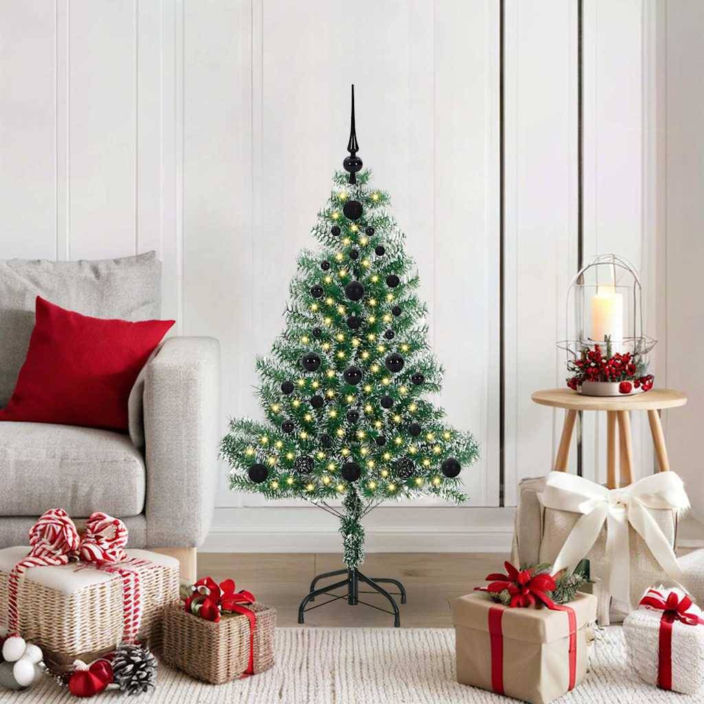 Ein kleiner, geschmückter Weihnachtsbaum mit Lichtern steht in einem gemütlichen Wohnzimmer. Geschenkkartons mit Schleifen liegen auf dem Boden daneben.